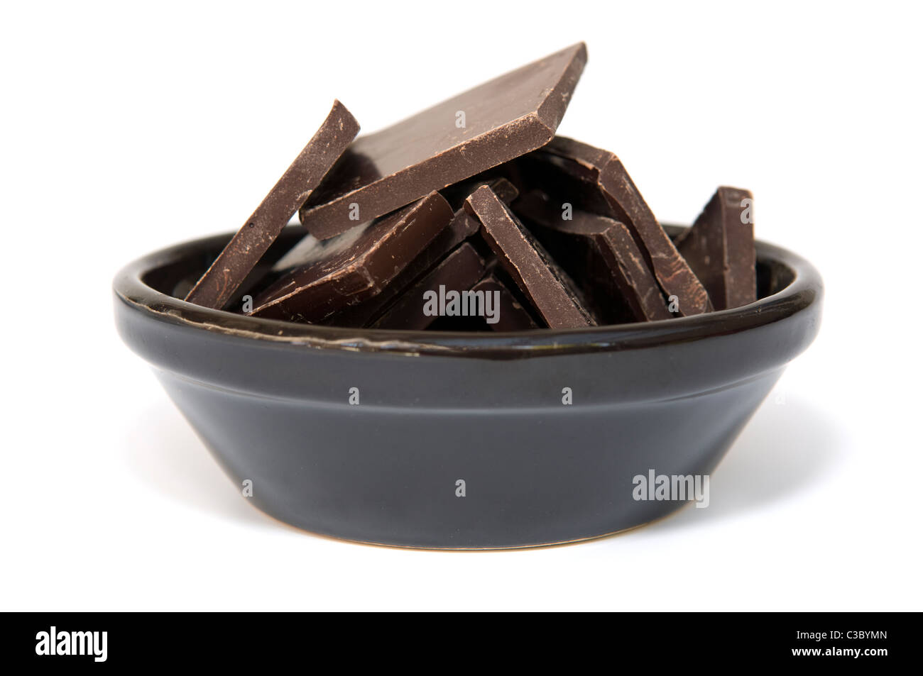Studio shot of a pile of plain broken chocolate pieces against a white background in dark brown bowl Stock Photo