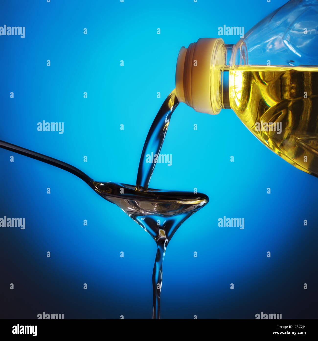 pouring olive oil on spoon, blue background Stock Photo