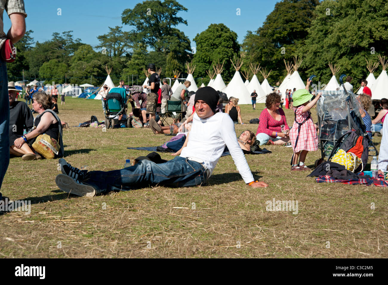 Man in a woolly hat sitting down on the grass at the Port Eliot Literary Festival St Germans Cornwall UK Stock Photo