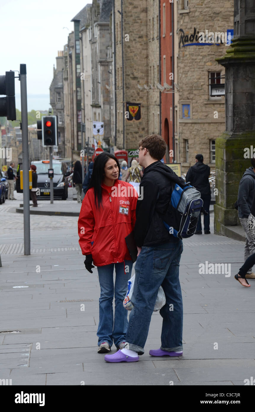 A female charity worker for Shelter stops a member of the public and attempts to get them to sign up to make contributions. Stock Photo
