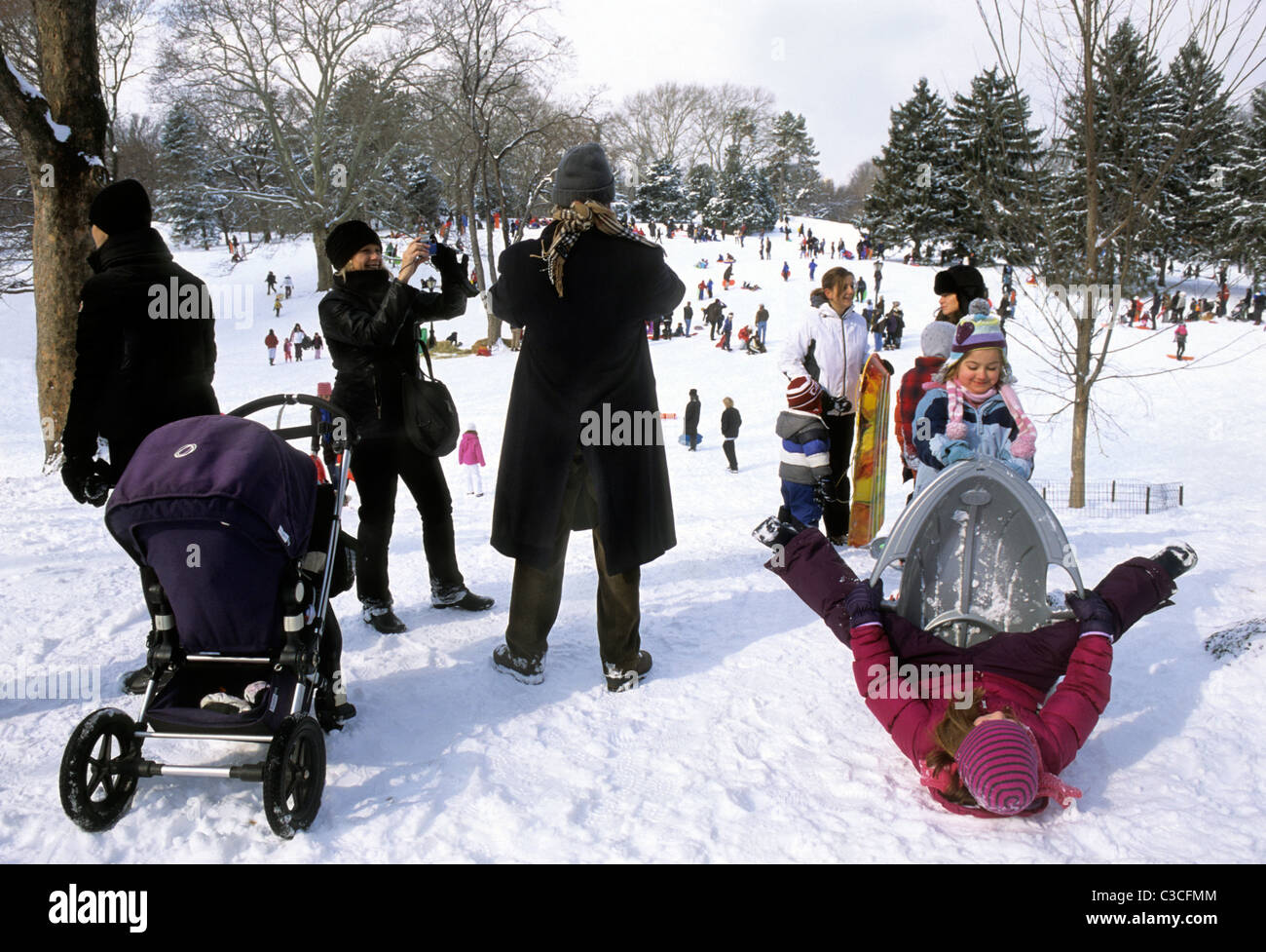 New York City Groups of people in Central Park enjoying winter activities. Families with children playing in the snow on Cedar Hill. Upper East Side. Stock Photo