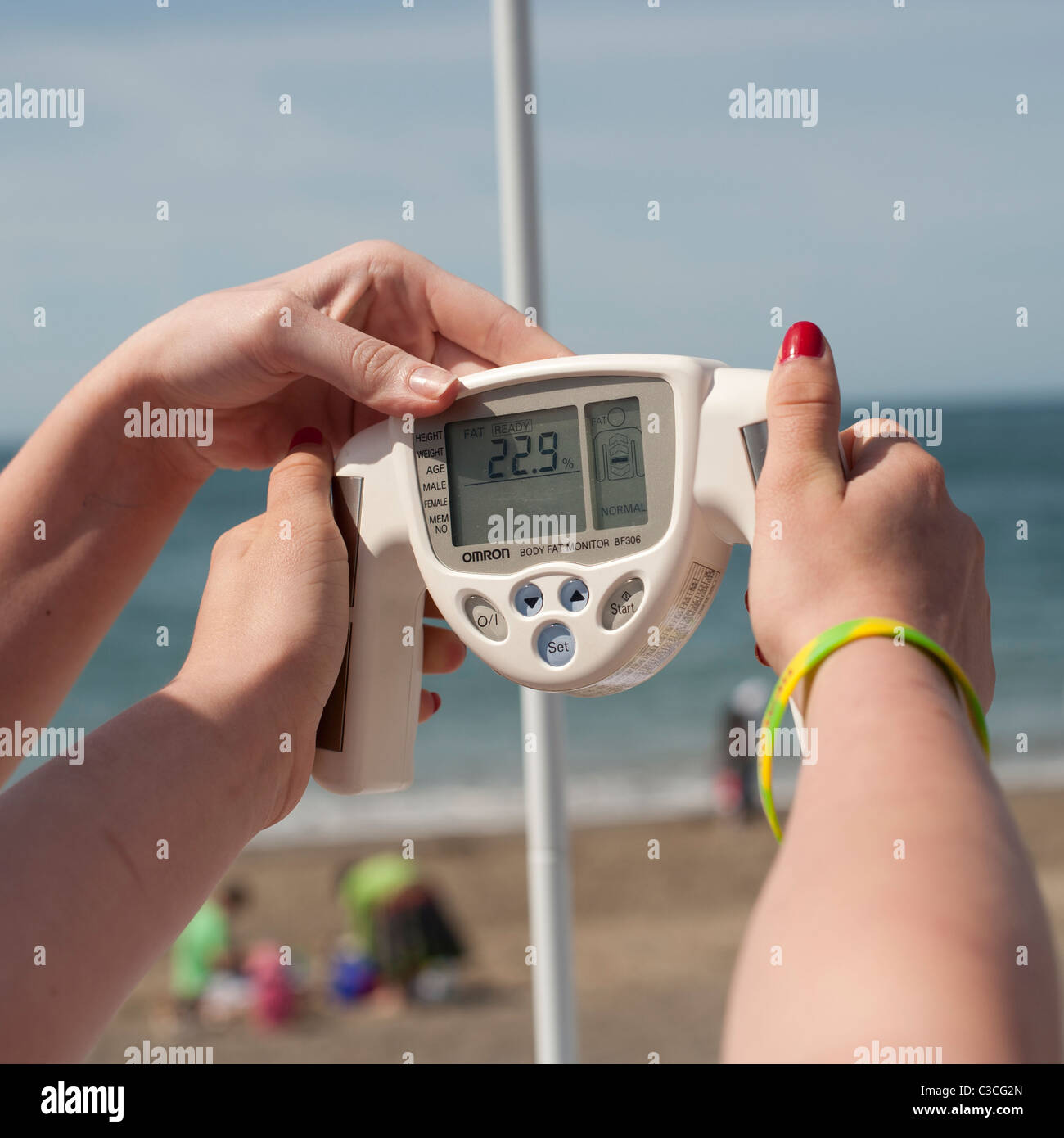 a person having a free checkup using an OMRON hand held body fat monitor  Stock Photo - Alamy