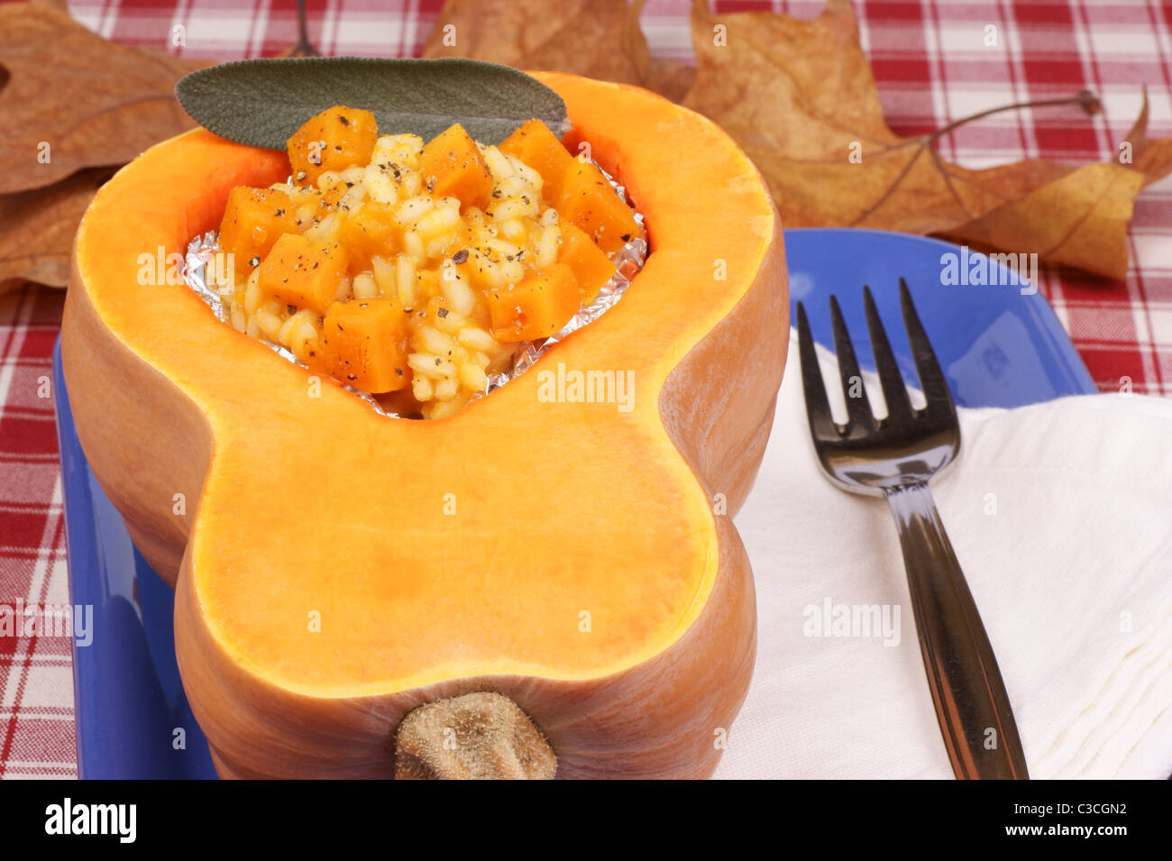 Half pumpkin filled with pumpkin risotto served on a blue plate Stock Photo