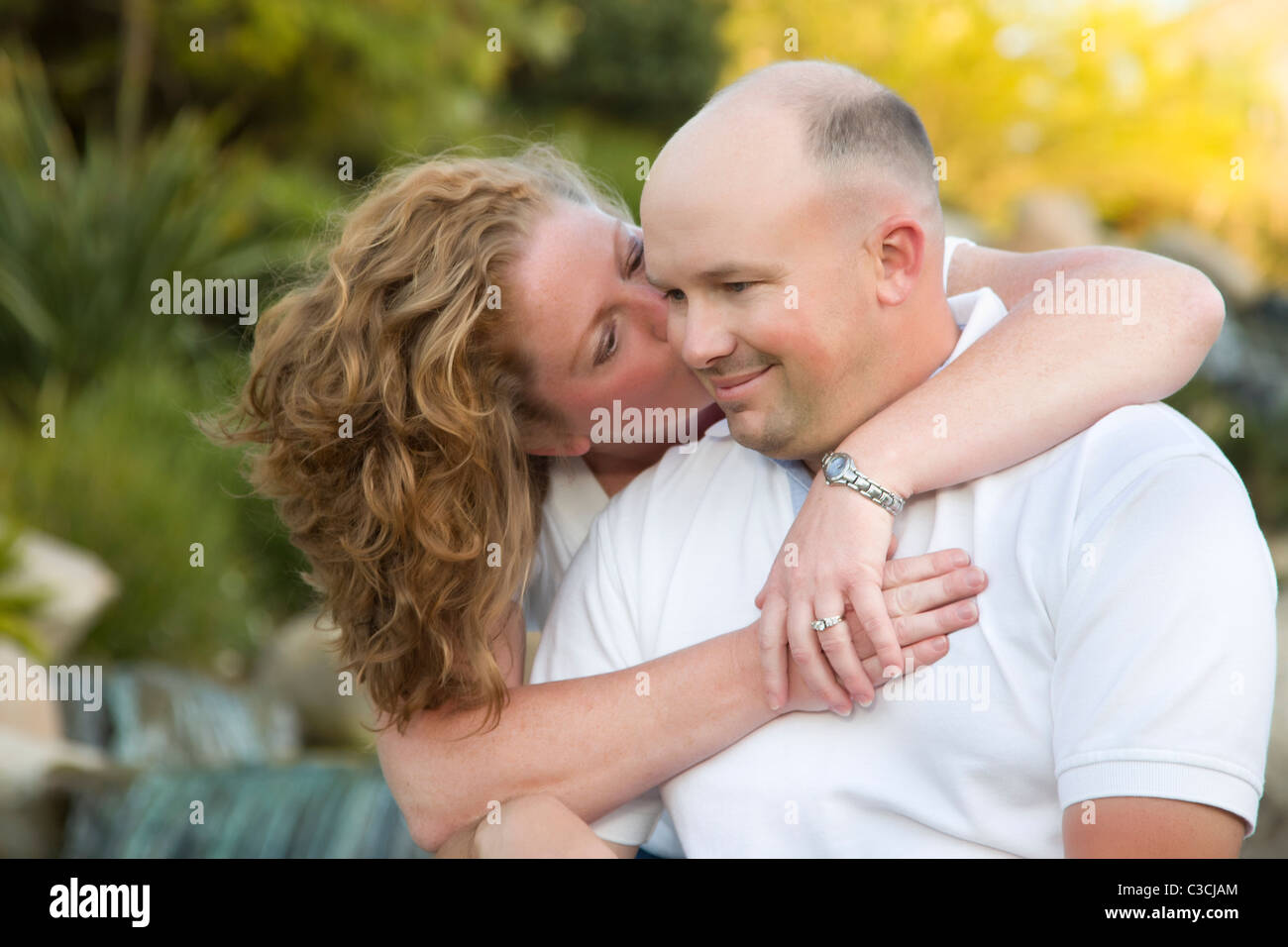 Happy, Attractive, Affectionate Couple Kiss on Cheek in the Park Stock