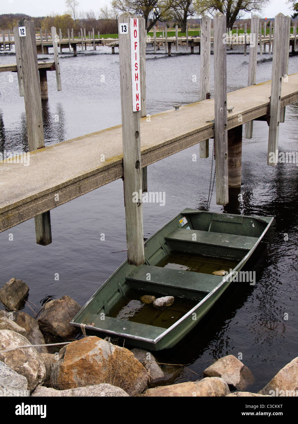 Water filled John Boat moored at public marina in Whitehall, Michigan. Overcast, bleak, spring day. Stock Photo