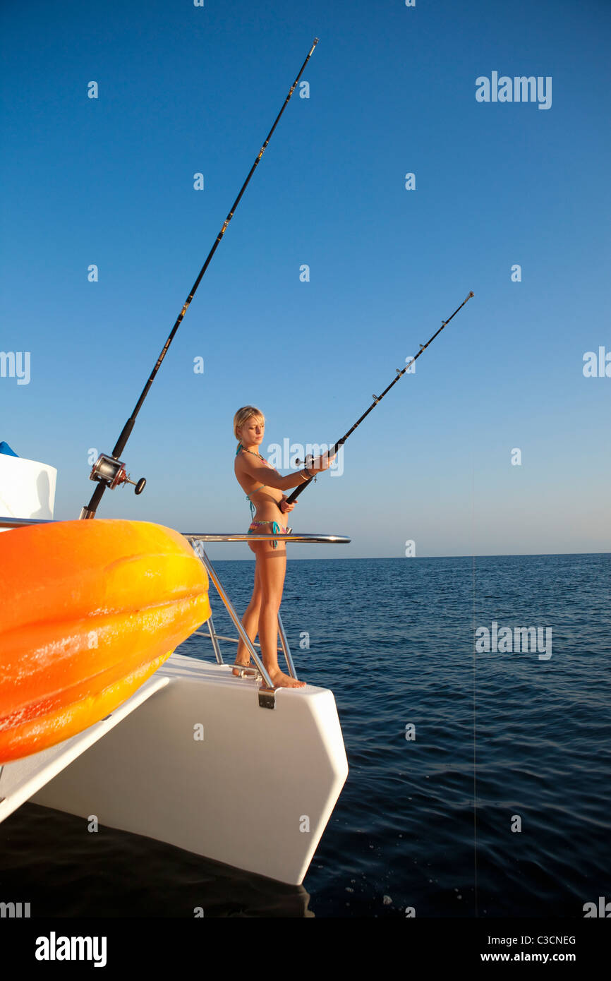young woman with fishing pole on yacht Stock Photo