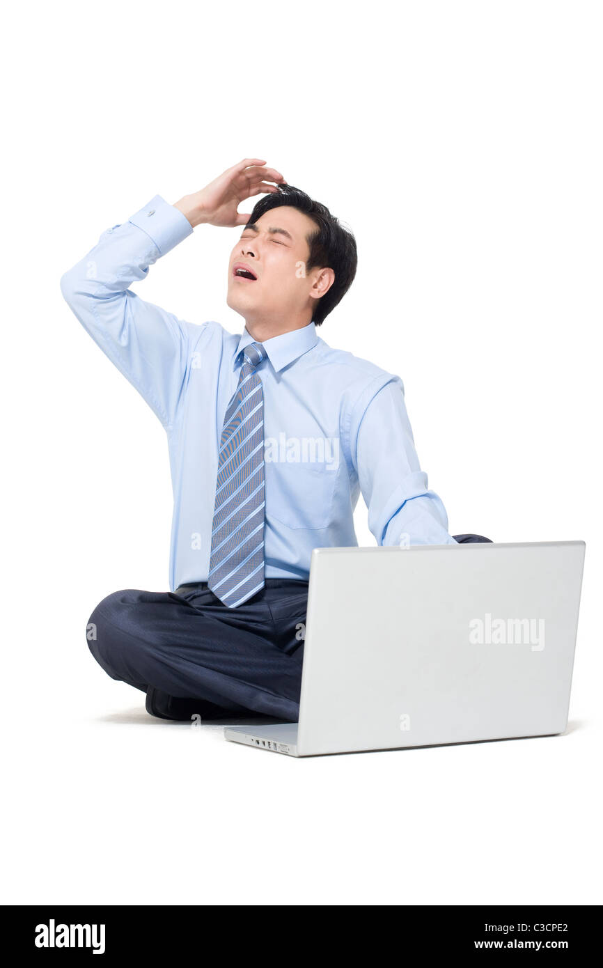 A frustrated businessman sitting on the floor with his laptop Stock ...