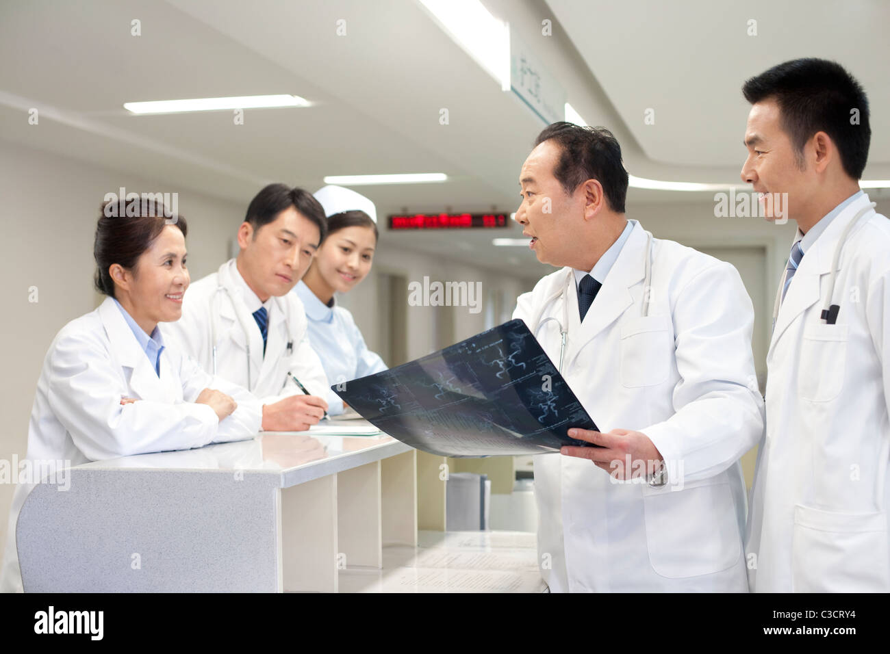 An older doctor showing a X-ray image to fellow doctors Stock Photo