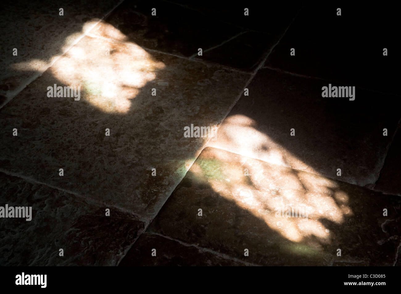 Sunlight  streaming through a  leaded window and casting shadow on an old stone flag floor. Stock Photo