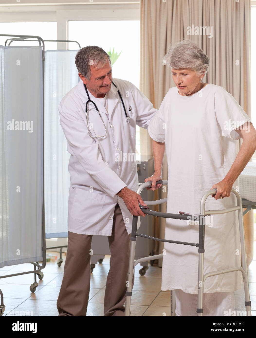 Senior doctor helping his patient to walk Stock Photo - Alamy