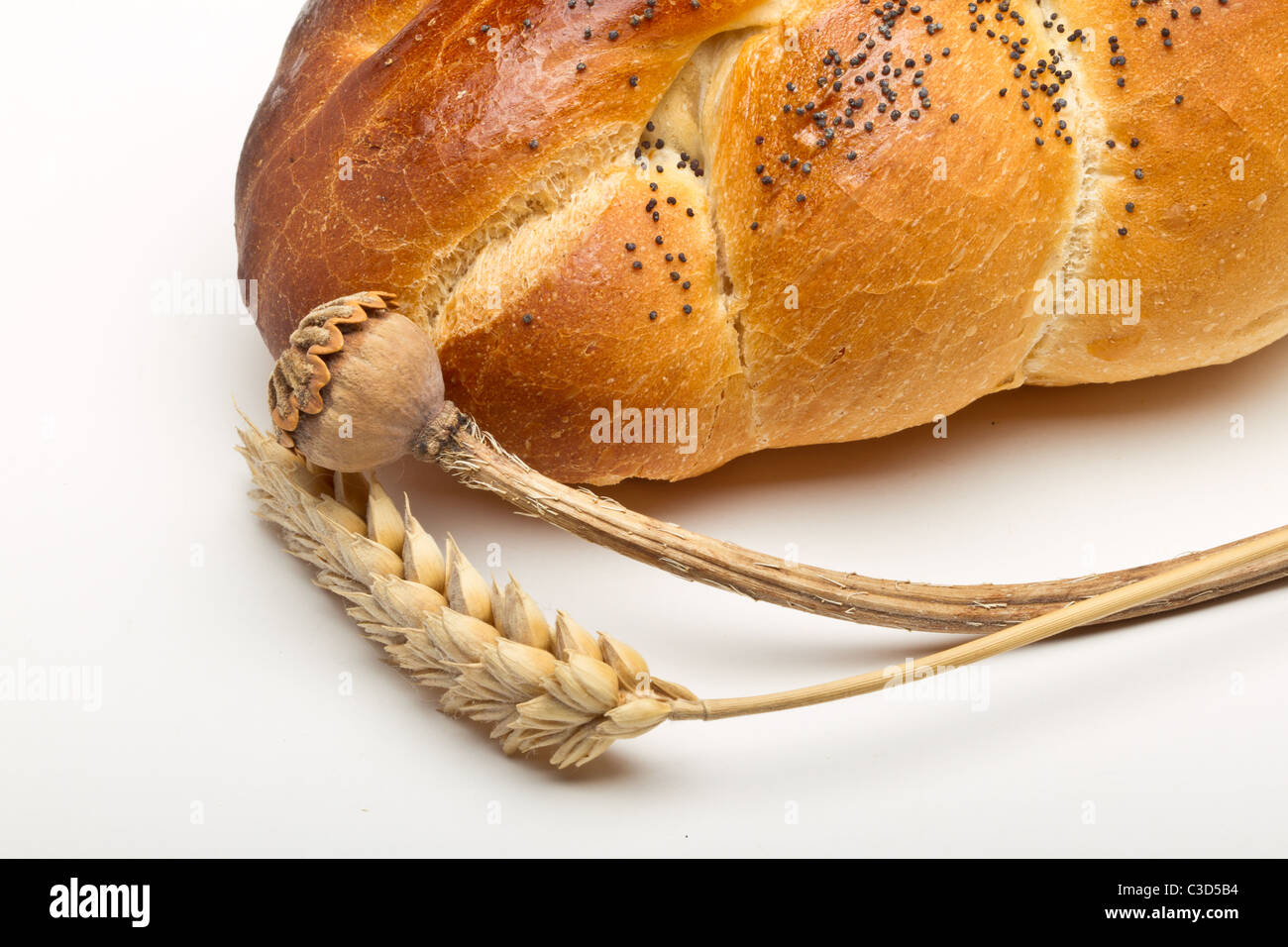 Dried cereal ear and poppy stem with rustic bread concept. Stock Photo