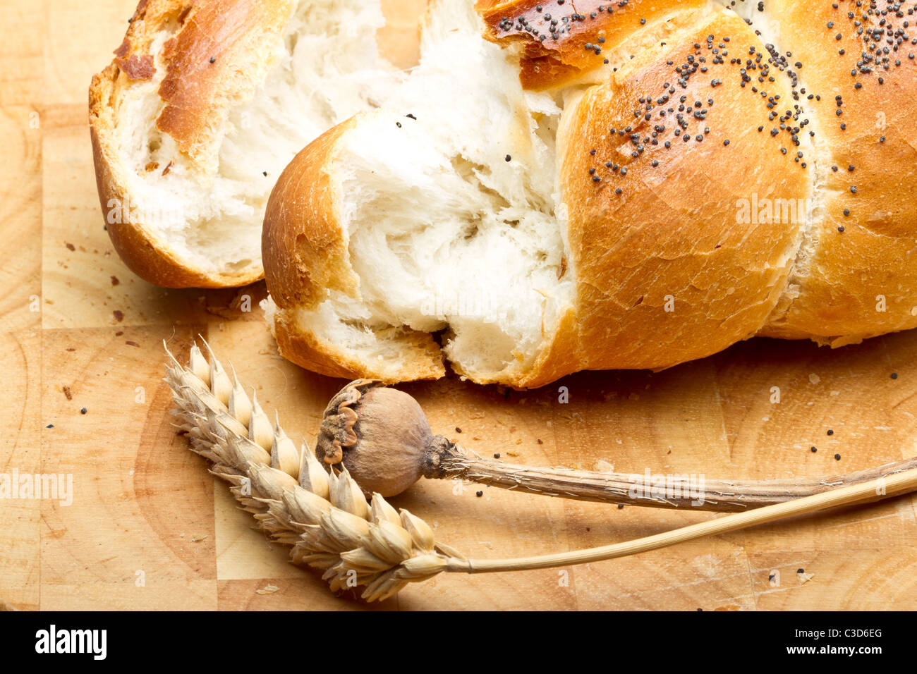 Rustic poppy seeded bread with dried cereal ear and poppy stem. Stock Photo