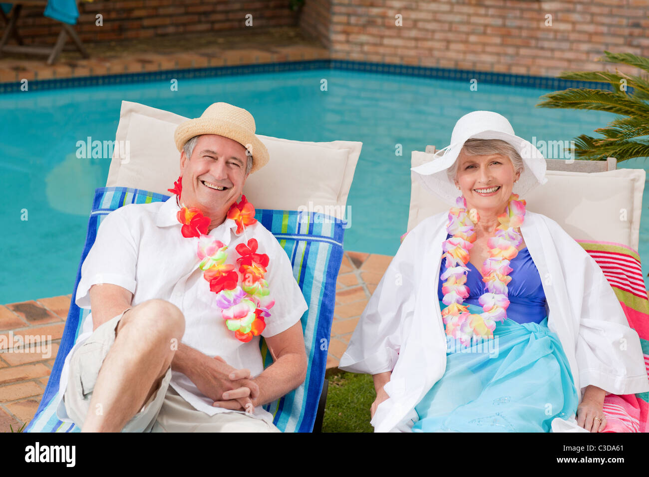 Senior couple lying down beside the swimming pool Stock Photo - Alamy