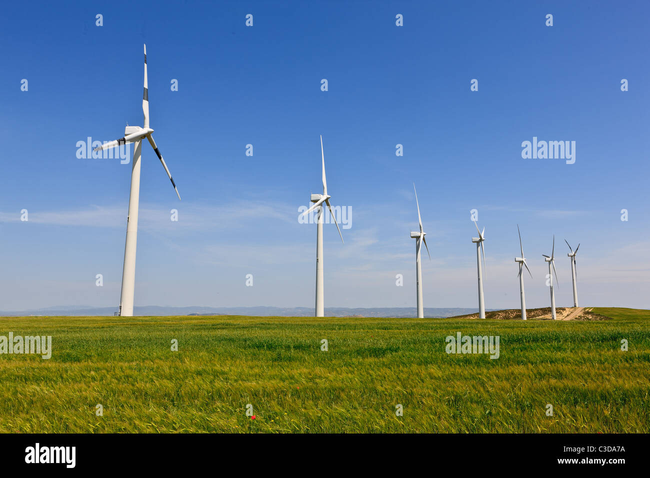Wind turbines in green field over cloudy sky Stock Photo - Alamy