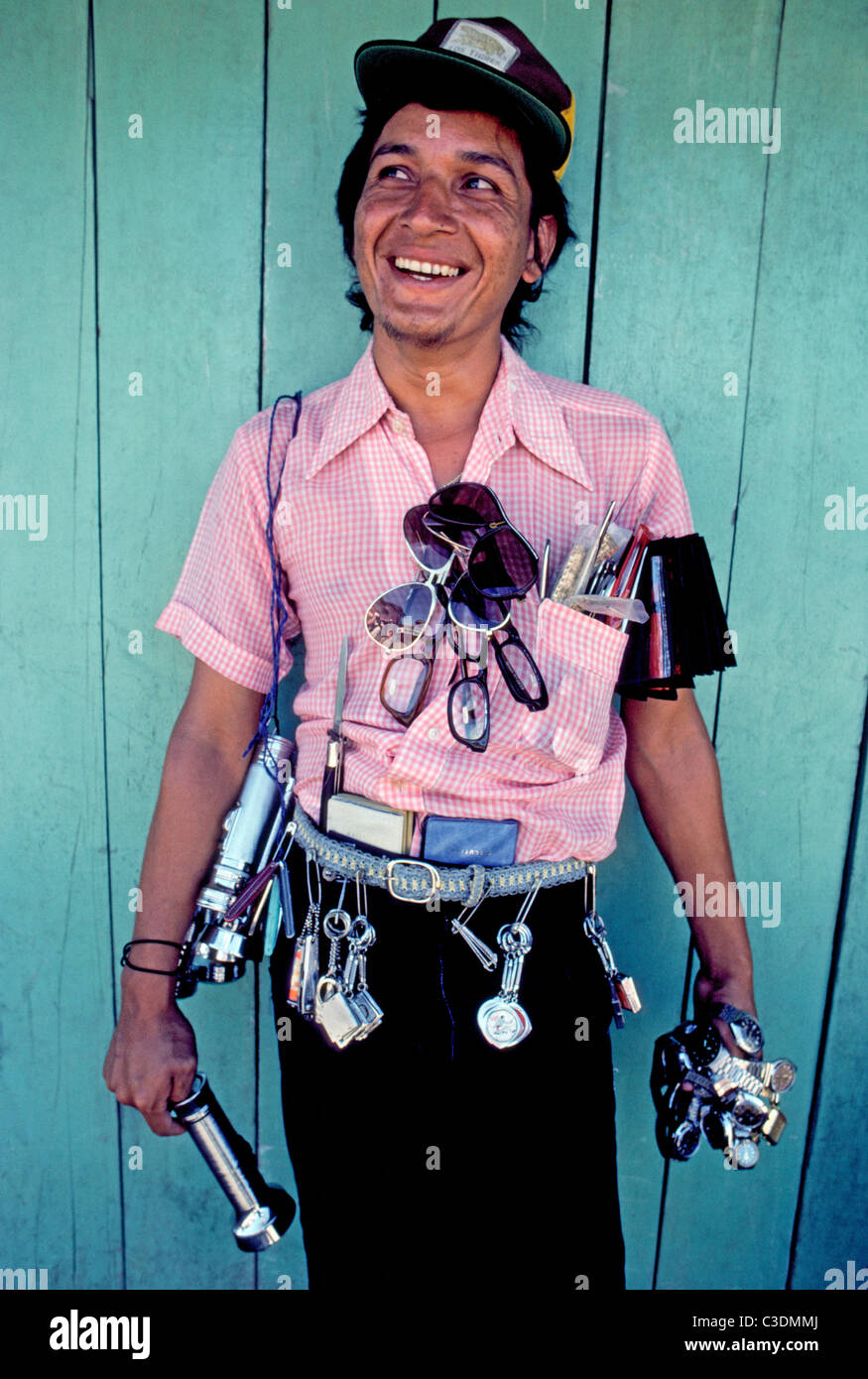 Eyeglasses, watches, flashlights and other items decorate this smiling street vendor in Coca City, an Amazon rainforest town in Ecuador, South America. Stock Photo