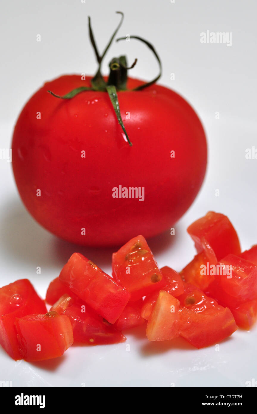 A whole and diced tomato sit on a white background. Stock Photo