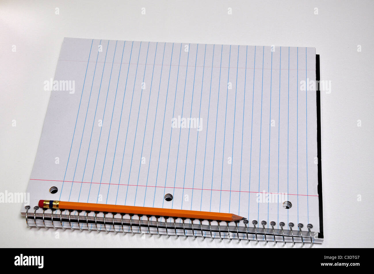 A standard size notebook with a pencil is sitting on a white background Stock Photo