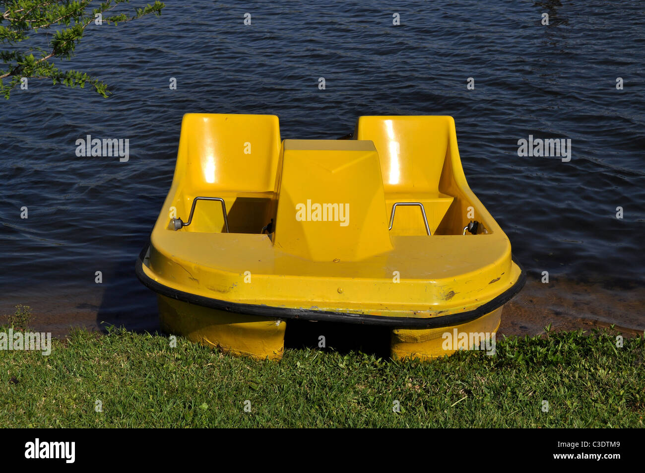 A yellow paddle boat on land at a lake Stock Photo