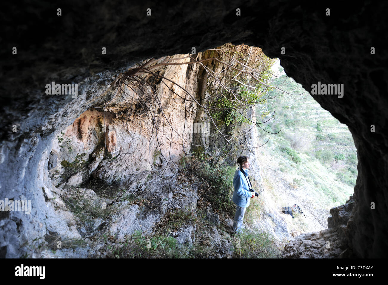 woman hiker standing in a cave, looking out,  near Benimaurell, Vall de Laguart, Alicante Province,Valencia, Spain Stock Photo