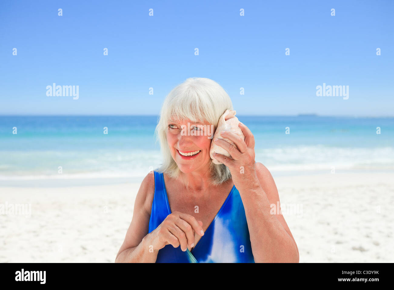 Woman listening to her shell Stock Photo - Alamy
