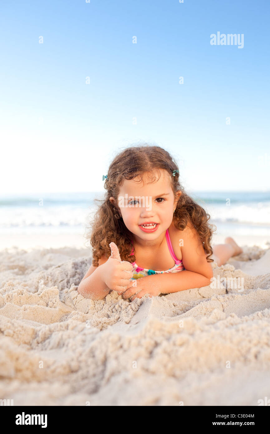 Little girl lying down on the beach Stock Photo - Alamy