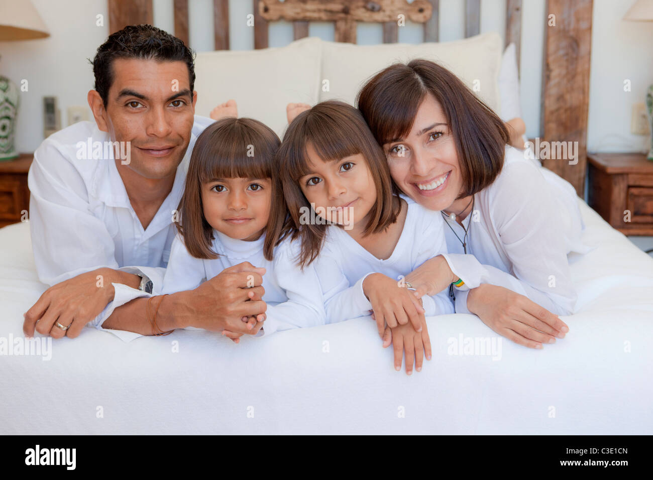 couple with two daughters on bed Stock Photo