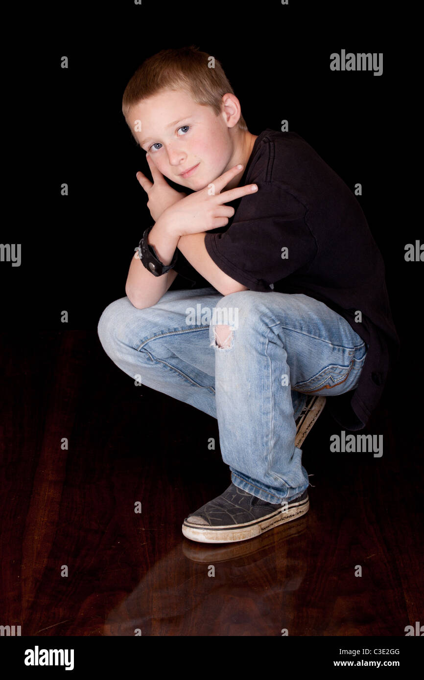 A photograph of a young boy with his arms crossed and his fingers in a