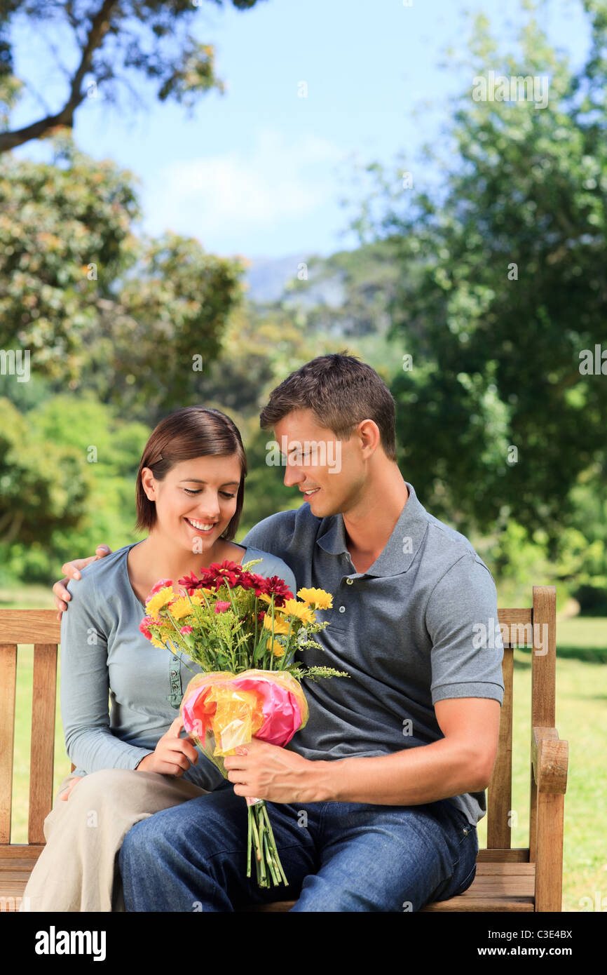 Man offering flowers to his girlfriend in a park Stock Photo