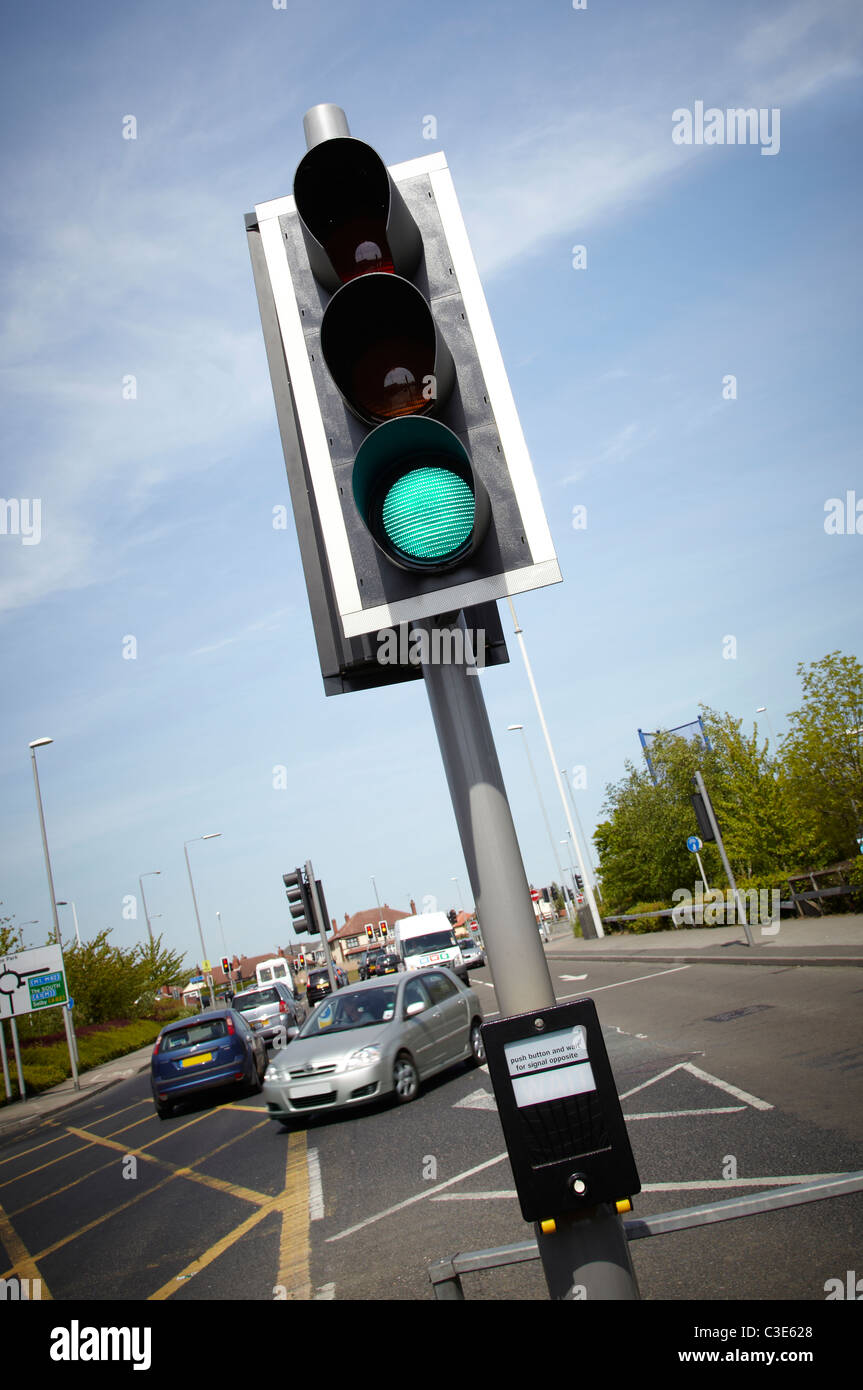 Pedestrian crossing button to press to activate traffic signal to stop. Shows traffic island in distance. Sunny day. Green light Stock Photo