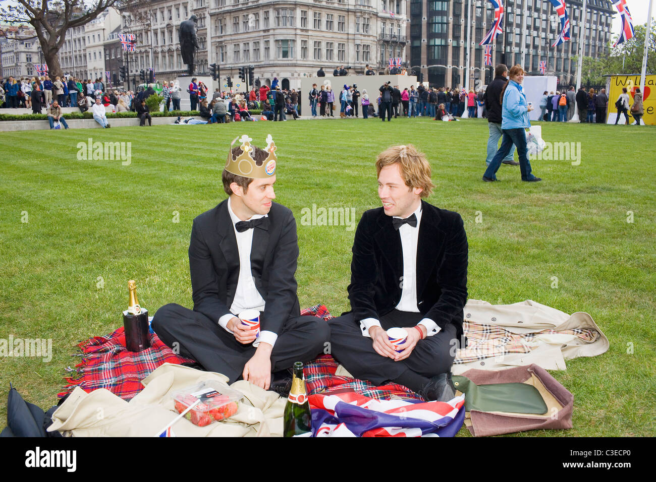 Two men in black suits and bow tie picnic in Parliament Square on the day of the royal weeding between Kate and William. Stock Photo