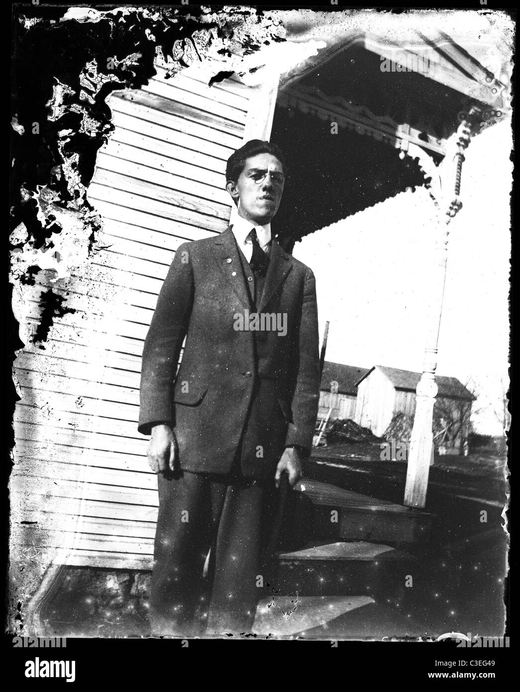 man standing stiff pose outside wooden house suit fashion male one only porch 1890s Stock Photo