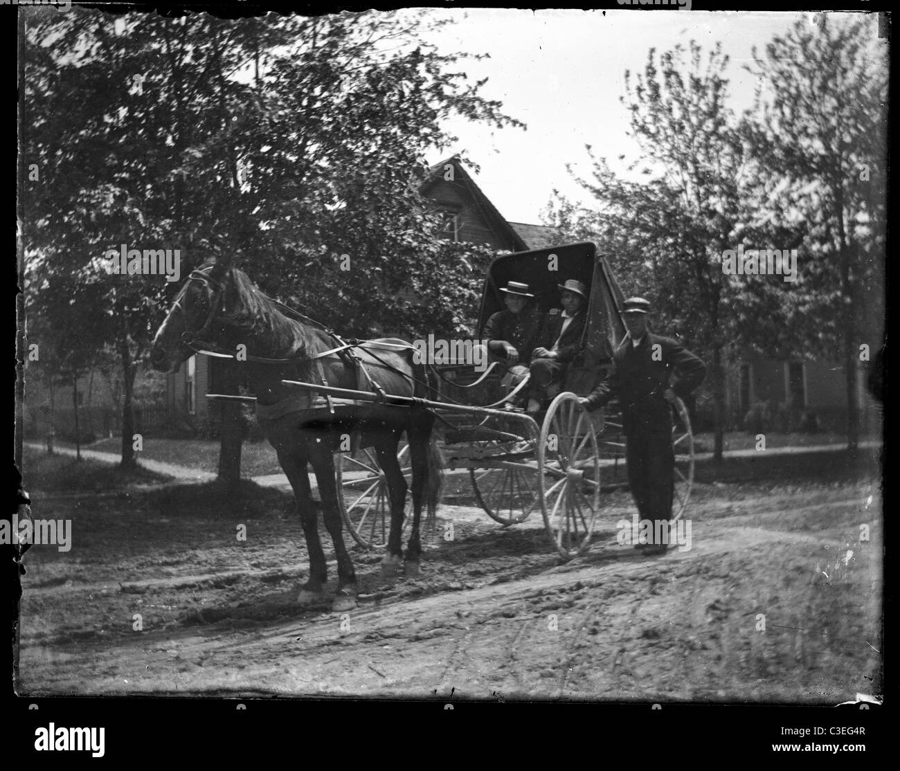 two men sitting in a horse and buggy dirt street road house transportation 19th century 1890s Stock Photo