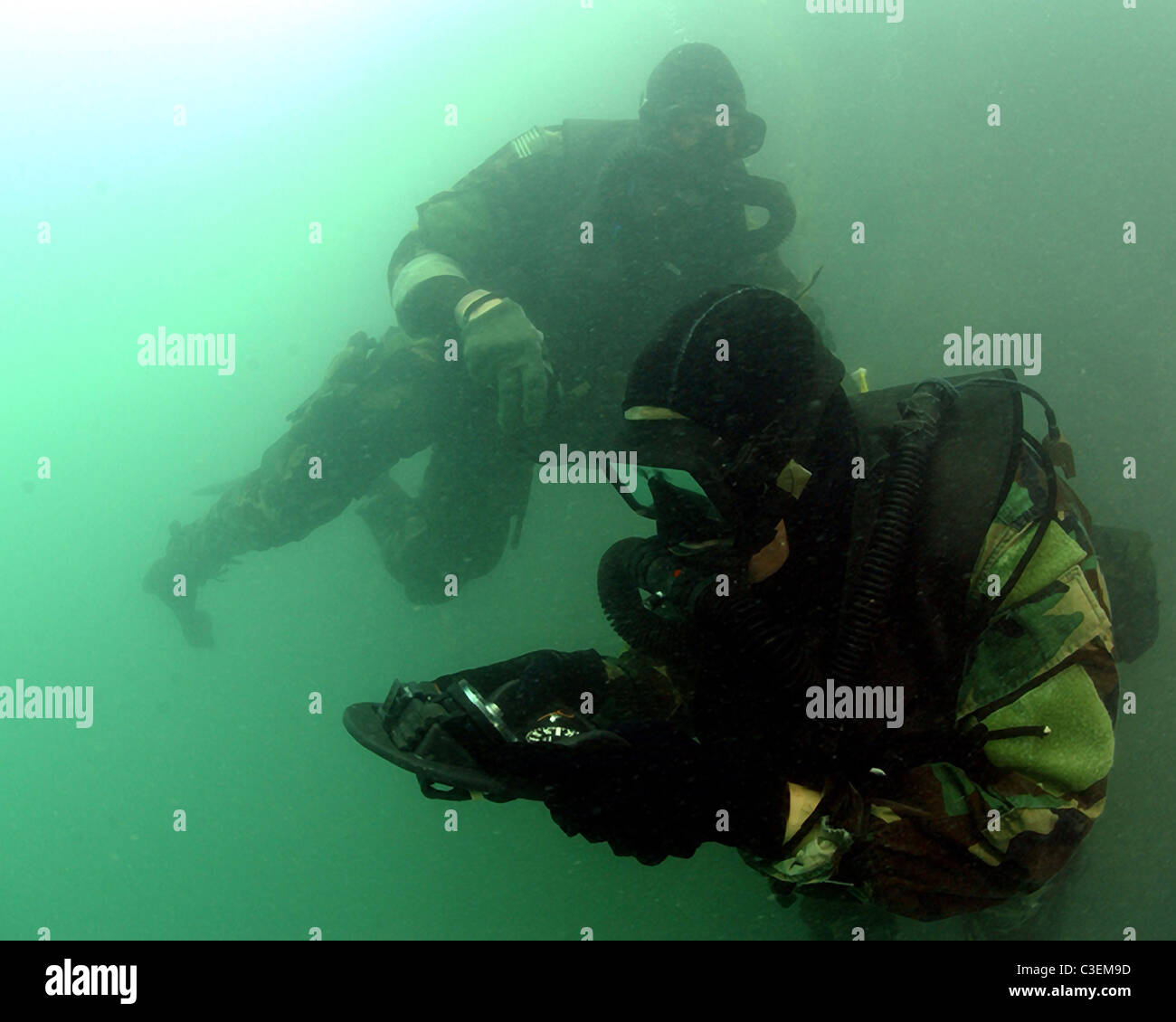 Two U.S. Navy SEALs navigate through murky waters during a Combat