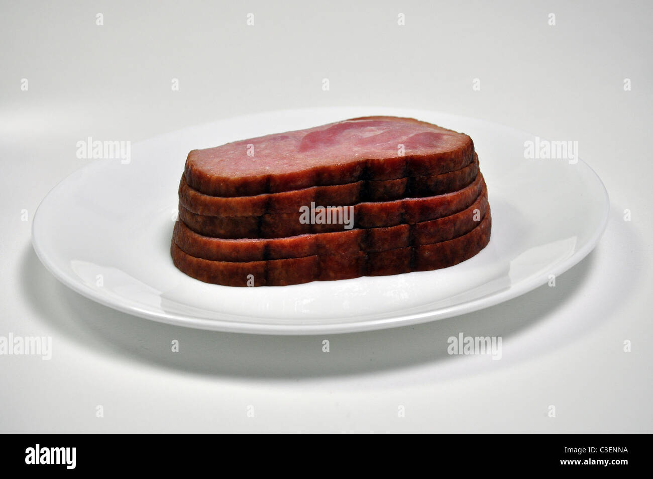 5 slices of ham on stacked on a plate. Stock Photo
