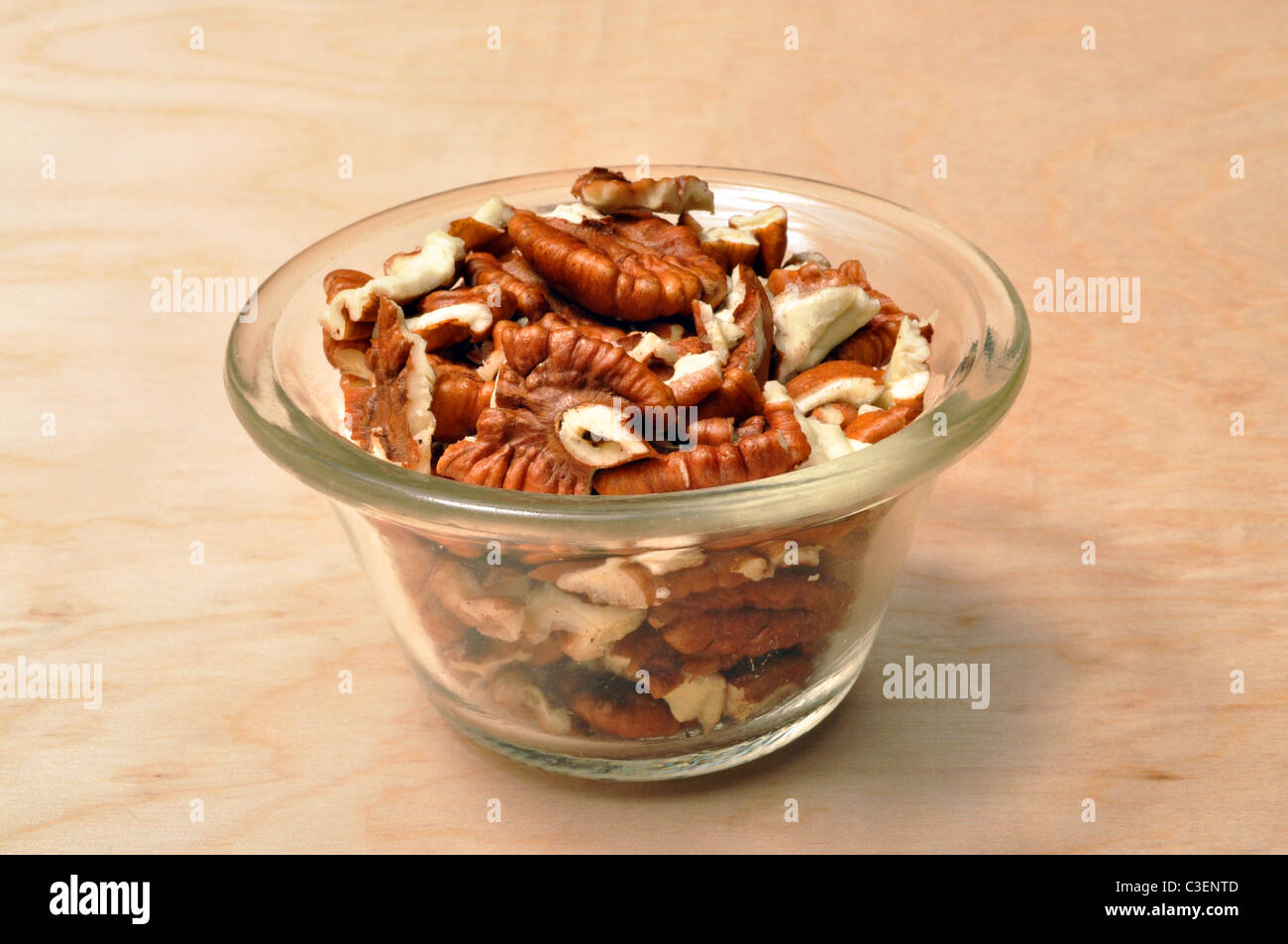 A small bowel on a brown table top full of shelled pecans Stock Photo
