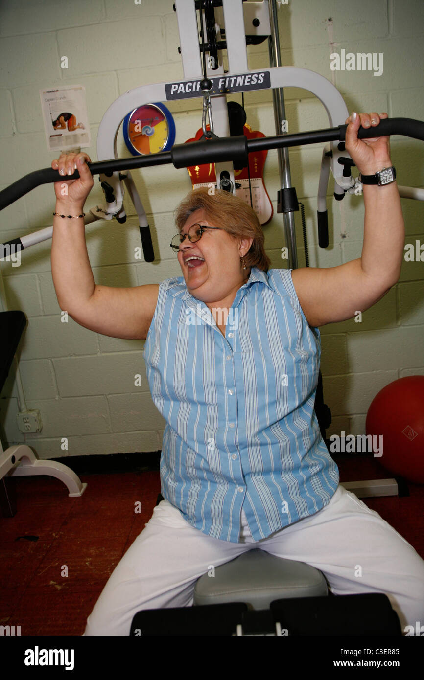 Hispanic female senior citizen having a good time working out in the fitness room at a senior center in Manhattan. Stock Photo