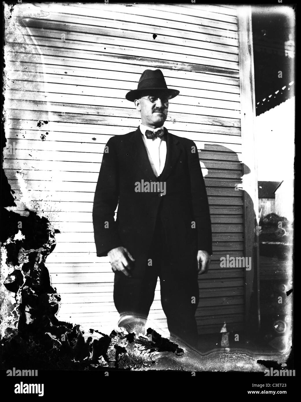 man in black suit next too clapboard wooden house 1890s Stock Photo