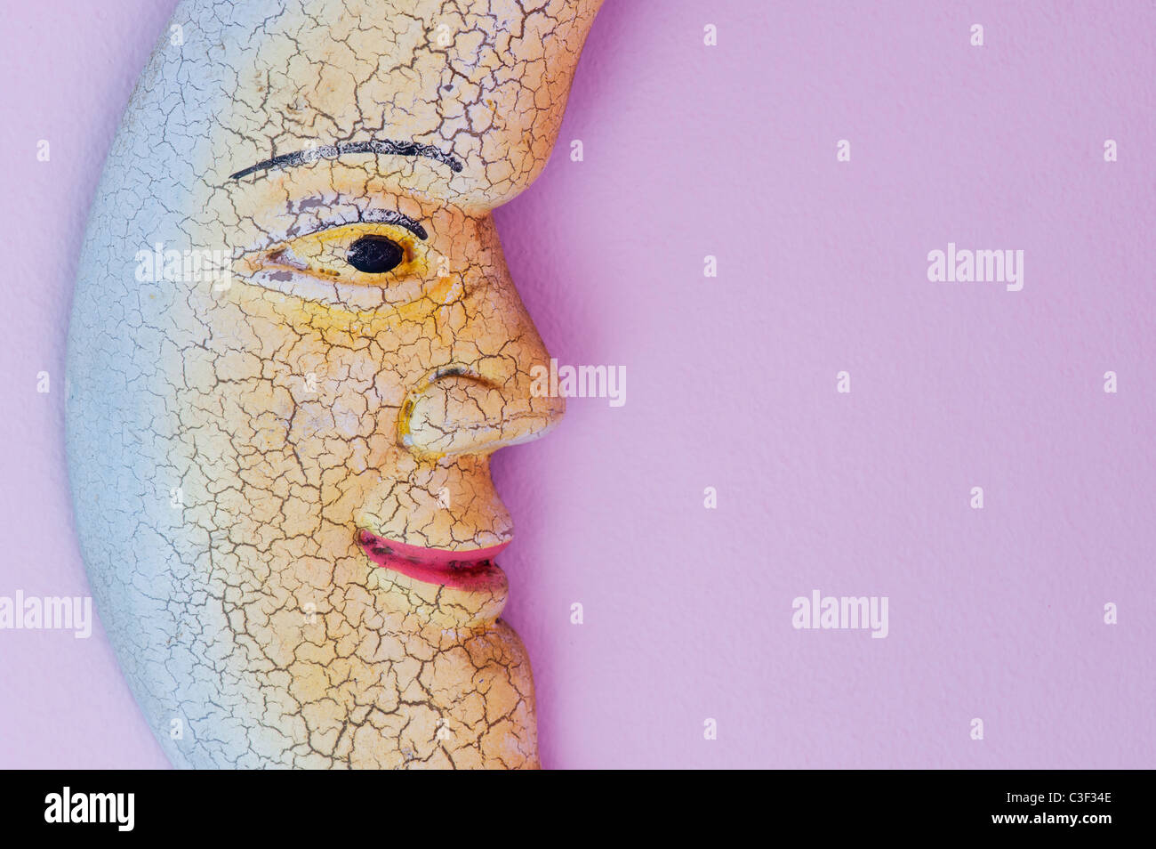Smiling colourful moon face wall ornament on a pink wall Stock Photo