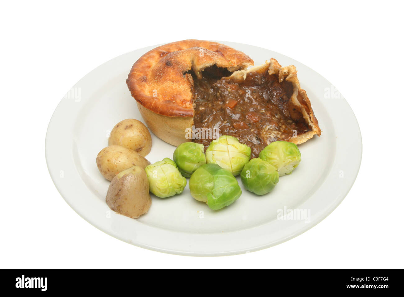 Meat and rich gravy pie with potatoes and brussel sprouts on a plate Stock Photo
