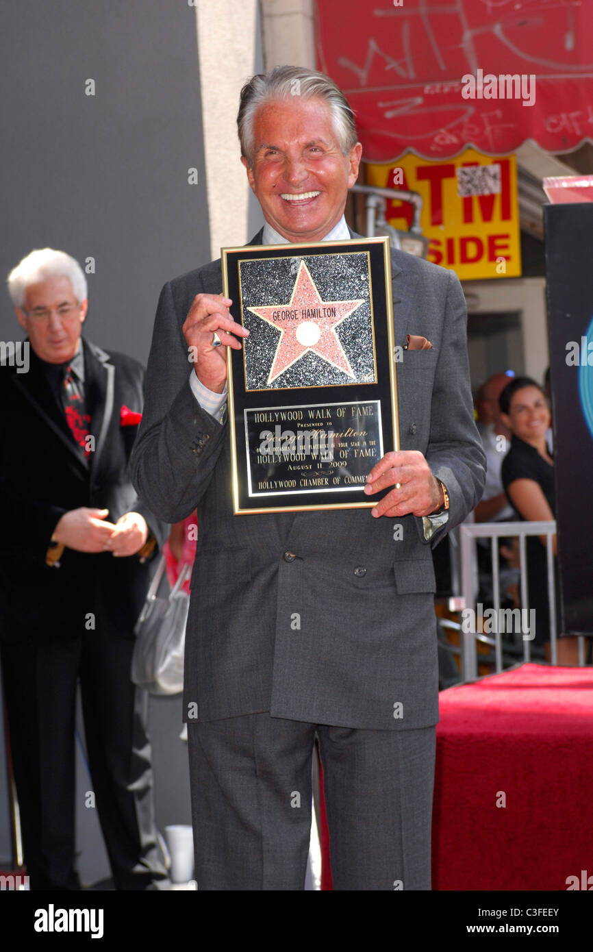 George Hamilton poses with a plaque after being honored on the ...