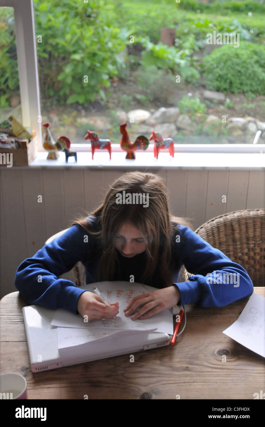 A 11 year old girl does her homework at the kitchen table Stock Photo