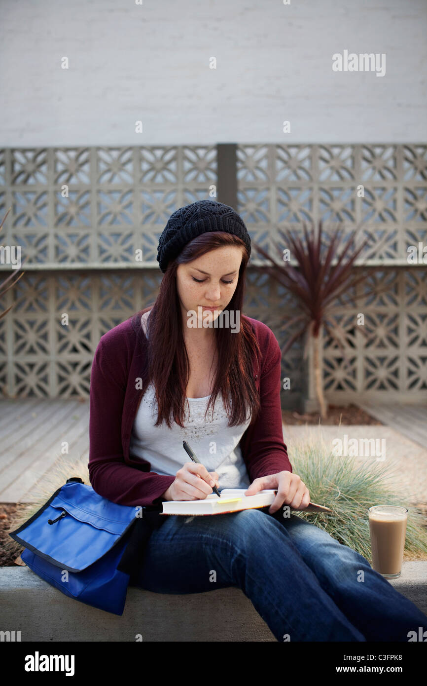 Caucasian woman writing in journal outdoors Stock Photo