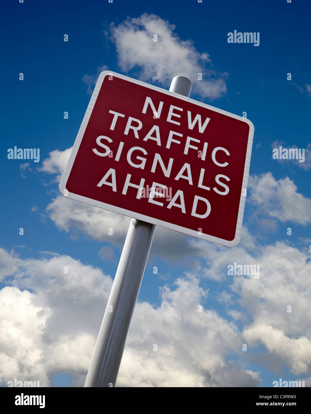 New Traffic signals ahead sign in England. Cut out against a Blue sky with white clouds. Stock Photo