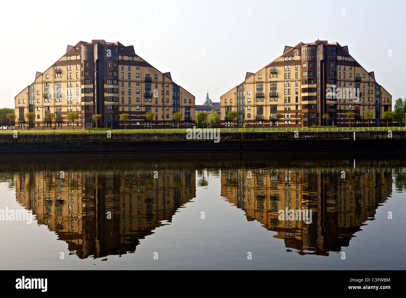 Modern apartment blocks reflected in the calm River Clyde with a tiny Govan Angel visible between them, Glasgow, Scotland, UK Stock Photo
