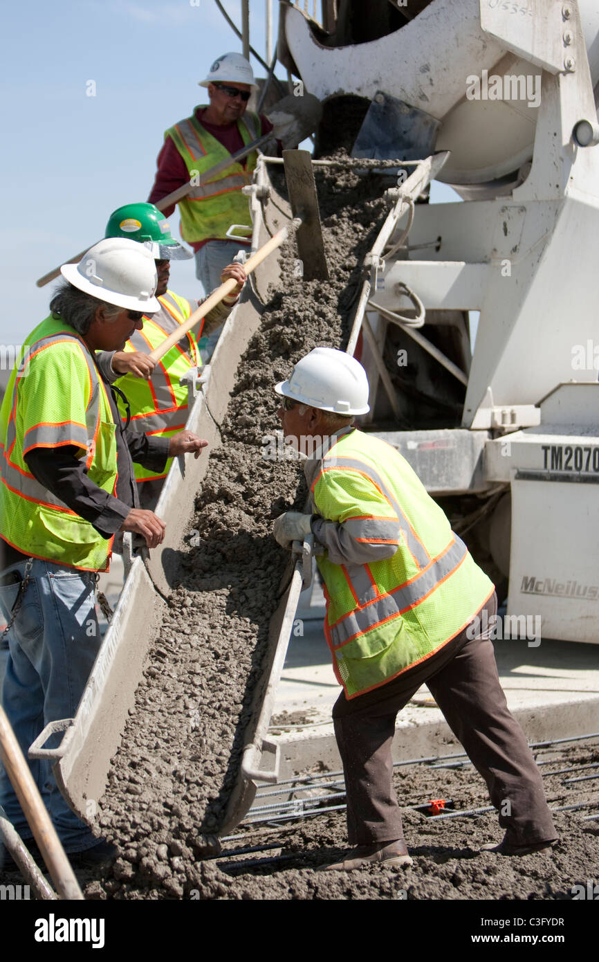 Male highway construction workers pour fresh concrete on stretch of  new highway in Texas Stock Photo