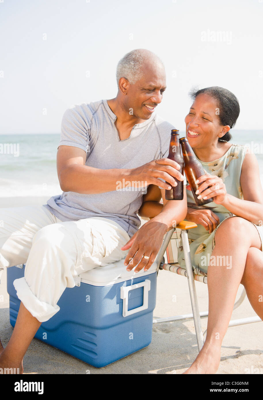 Black couple drinking beer on beach Stock Photo