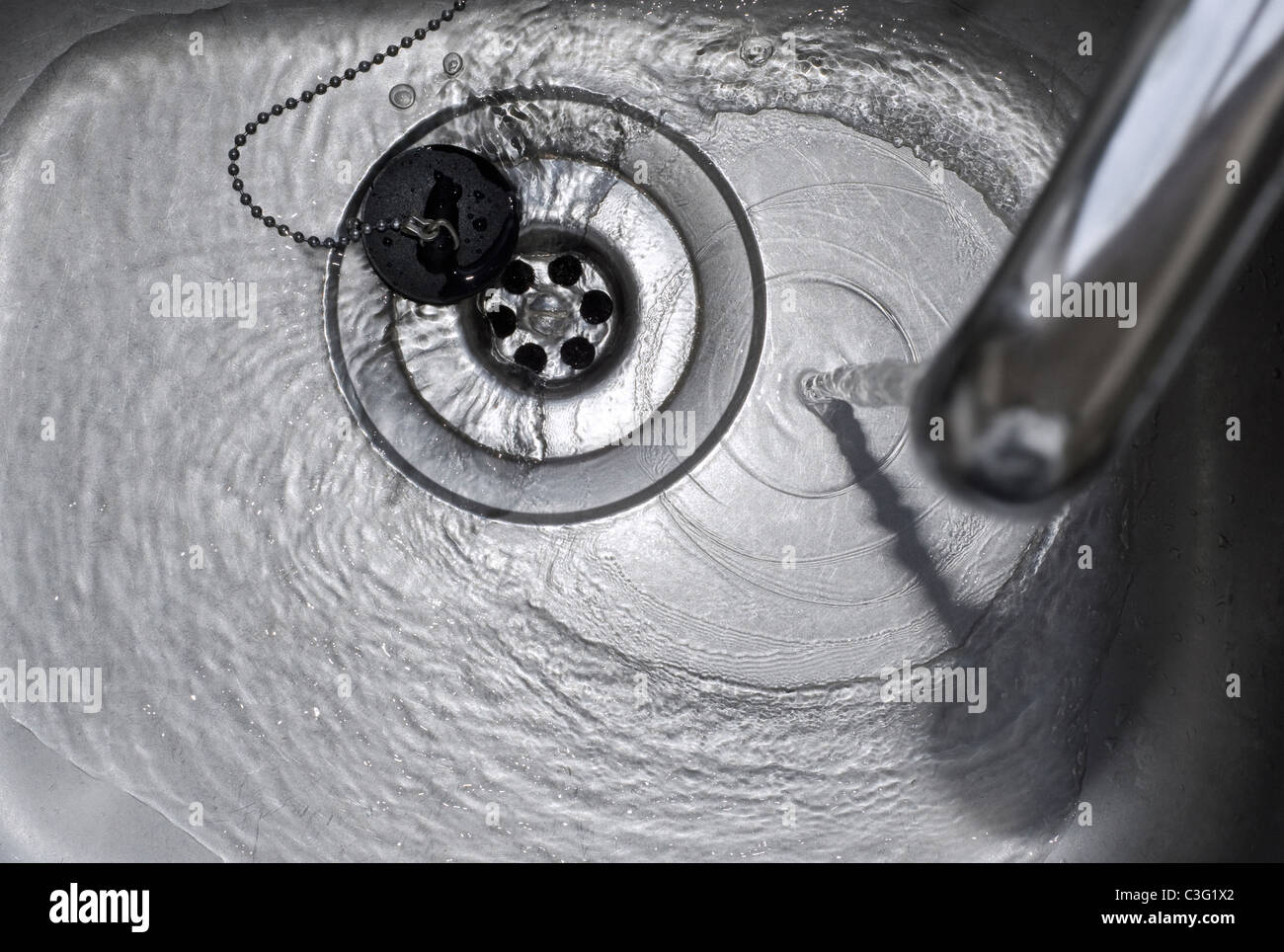 Running Water Draining Down the Plughole in Kitchen Sink Stock Photo