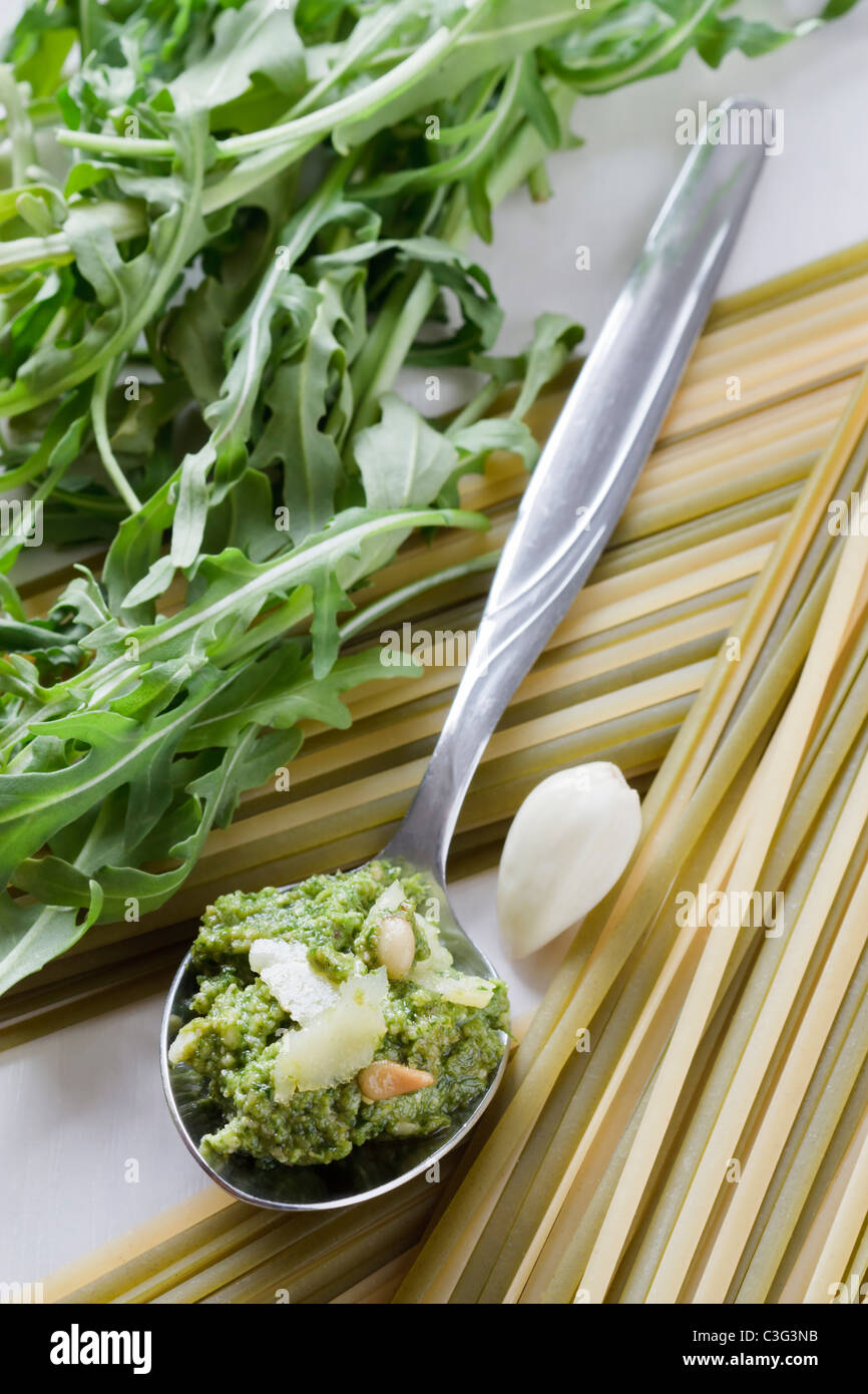Spoon with fresh prepared rocket pesto, parmesan, pine nuts, garlic and linguine. Stock Photo