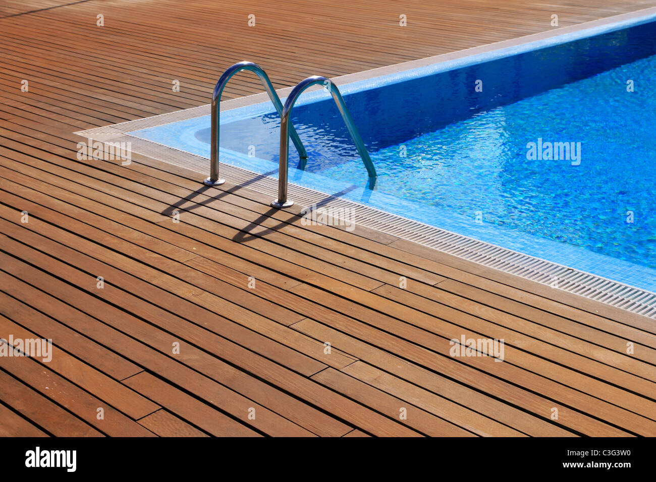 blue swimming pool with teak wood flooring stripes summer vacation Stock Photo