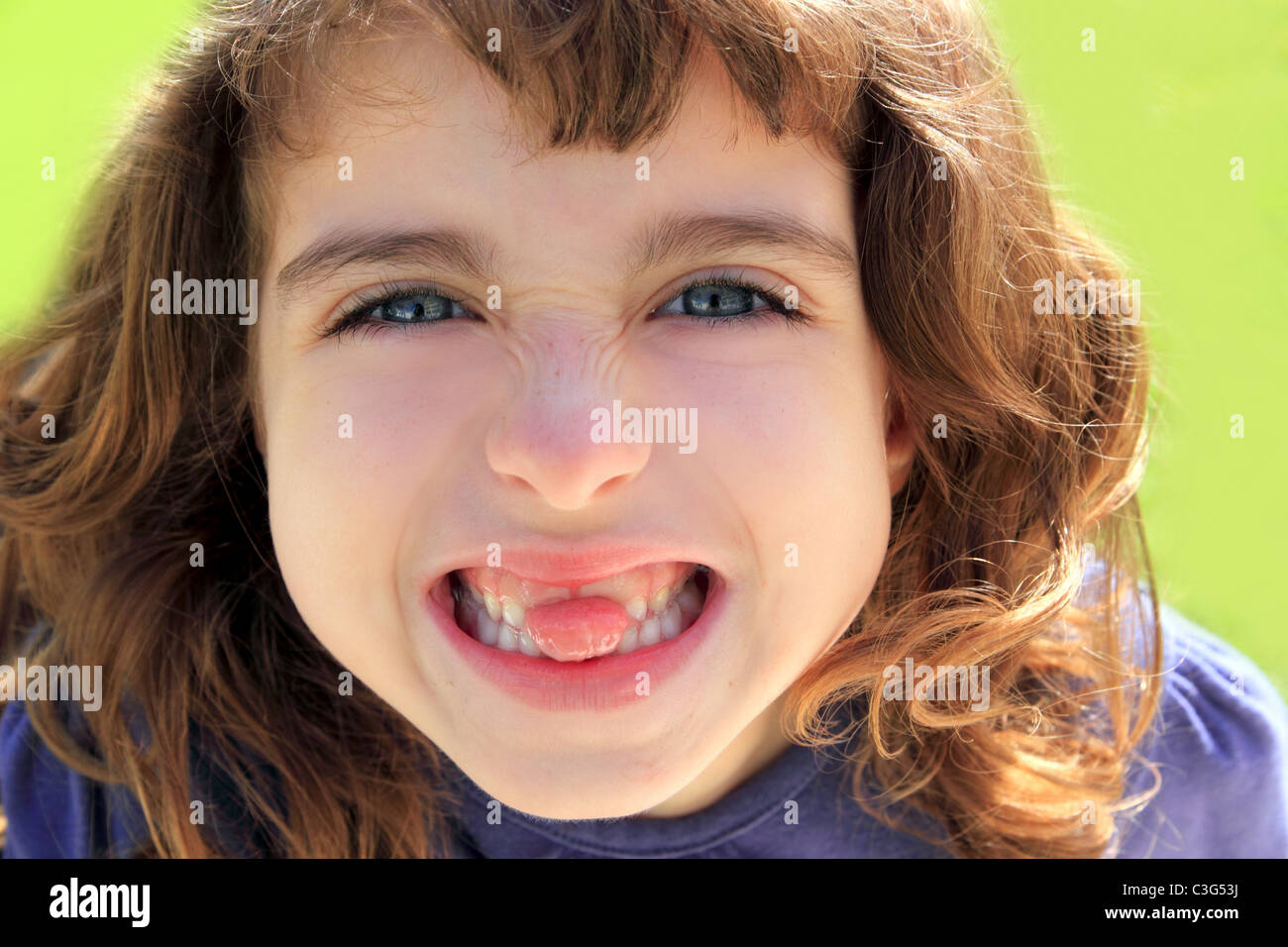 indented little girl sticking tongue between teeth smiling portrait